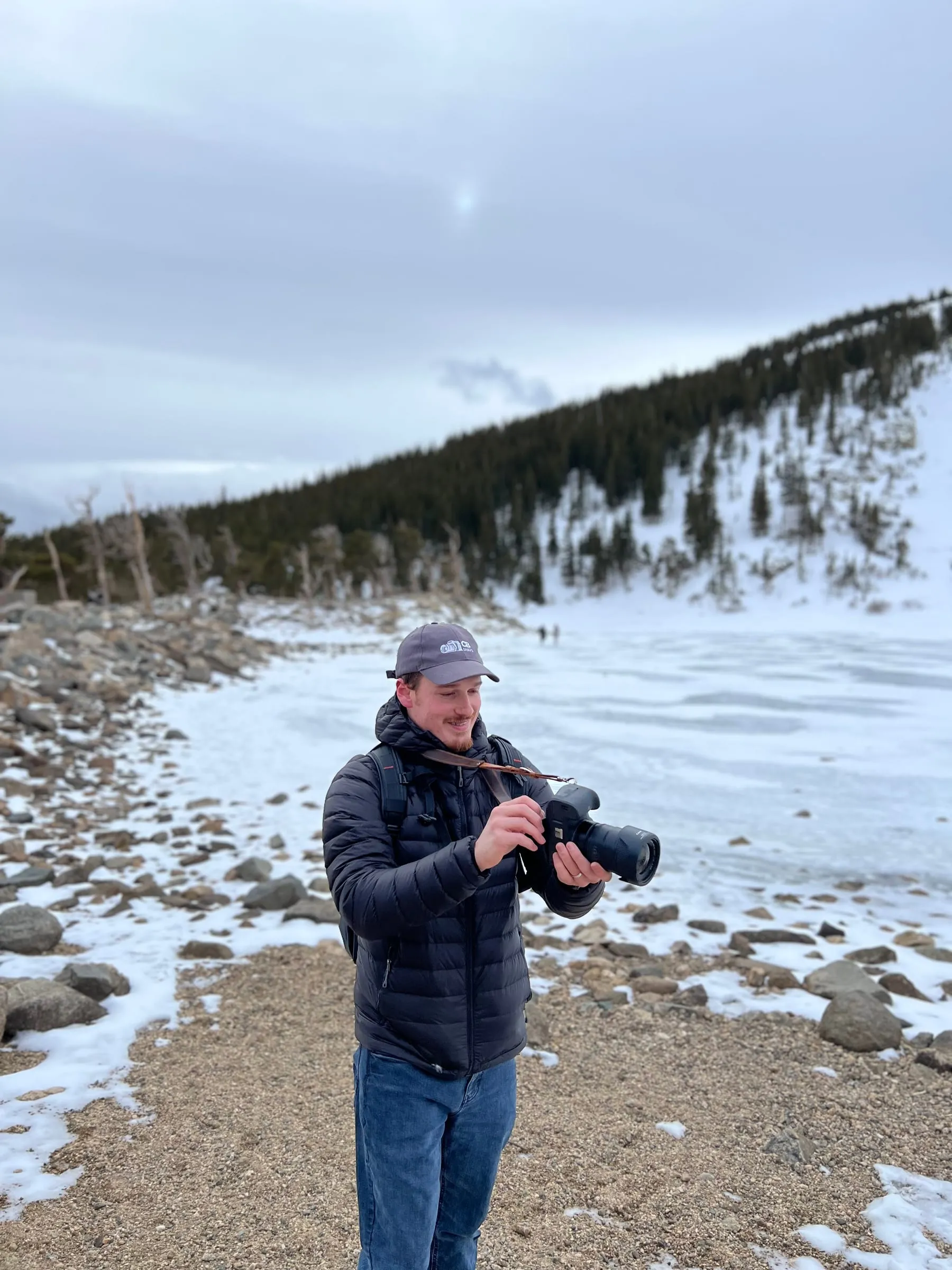 Christian standing at the edge of a frozen alpine lake with his camera