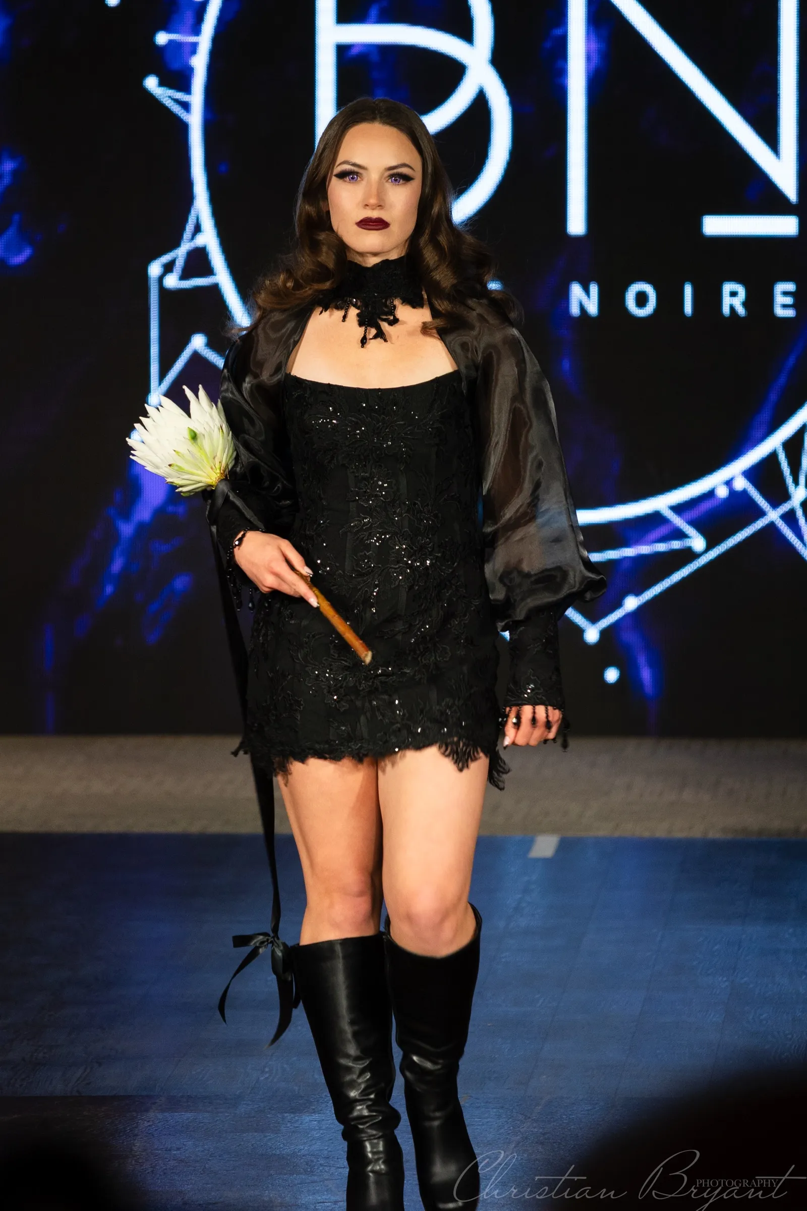 Model on a runway in front of an illuminated backdrop